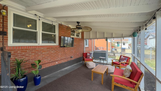 sunroom with lofted ceiling with beams, ceiling fan, and a wealth of natural light