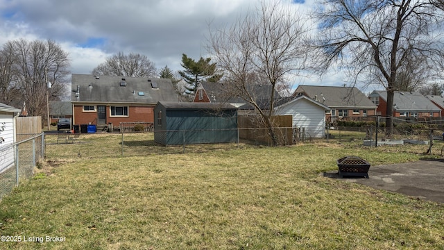 view of yard featuring a shed, an outdoor fire pit, an outdoor structure, and a fenced backyard