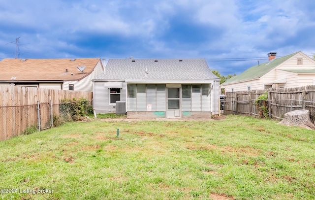 rear view of house featuring roof with shingles, a fenced backyard, a lawn, and central air condition unit