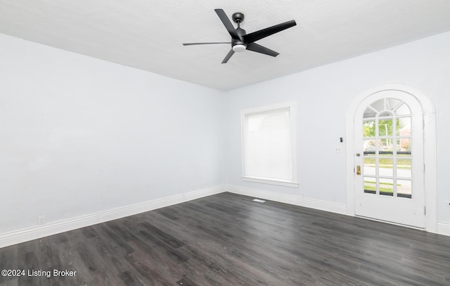 spare room featuring a ceiling fan, dark wood-style flooring, and baseboards