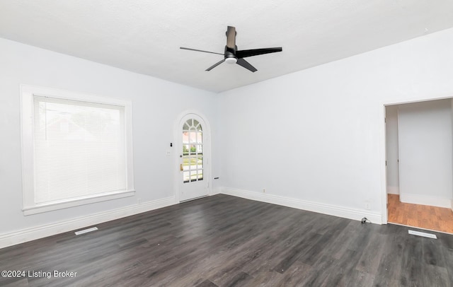 spare room featuring dark wood-style floors, baseboards, visible vents, and a ceiling fan