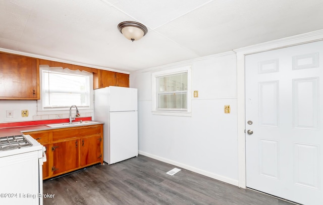 kitchen featuring white appliances, dark wood-style flooring, a sink, and brown cabinetry