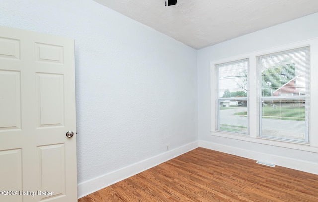 unfurnished room featuring light wood-type flooring, visible vents, and baseboards