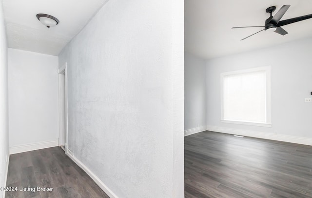 empty room featuring ceiling fan, baseboards, and wood finished floors