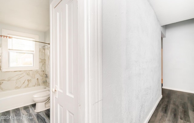 bathroom featuring toilet, baseboards, wood finished floors, and shower / bathing tub combination