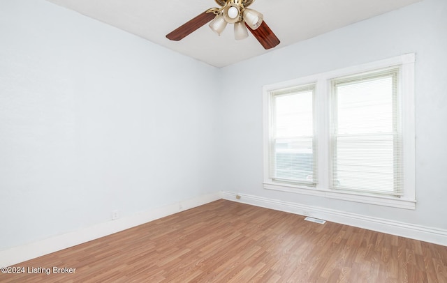 empty room featuring ceiling fan, light wood-type flooring, visible vents, and baseboards