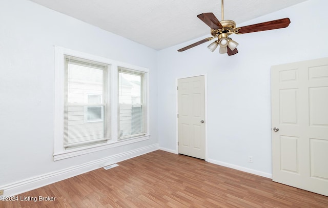 unfurnished room with a ceiling fan, visible vents, light wood-style flooring, and baseboards