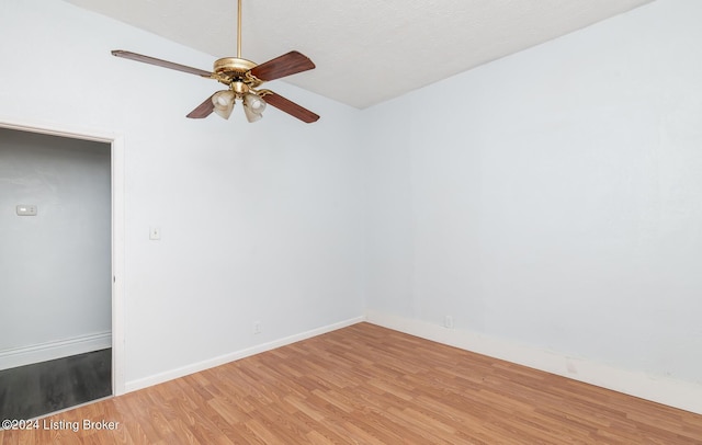 unfurnished room with ceiling fan, light wood-style flooring, baseboards, and a textured ceiling