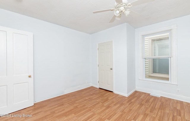 empty room with light wood-style floors, a textured ceiling, baseboards, and a ceiling fan