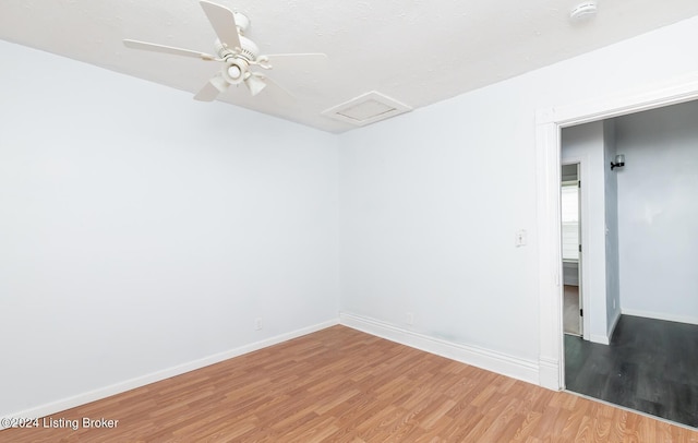 unfurnished room featuring light wood-style floors, attic access, baseboards, and a ceiling fan