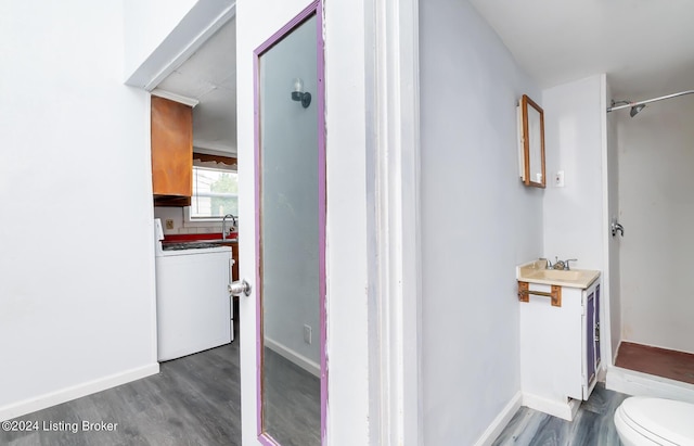 bathroom with baseboards, toilet, washer / clothes dryer, wood finished floors, and vanity