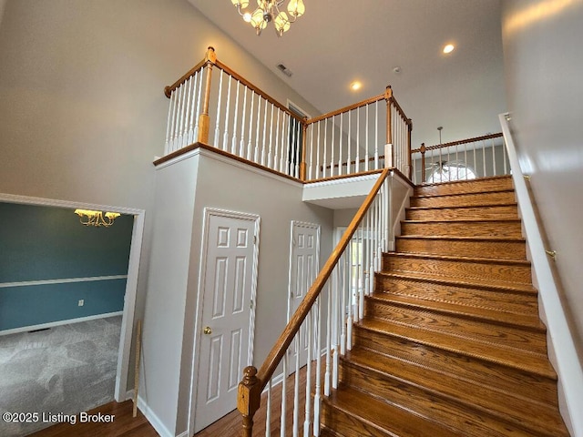 stairs featuring a notable chandelier, recessed lighting, a towering ceiling, carpet flooring, and baseboards