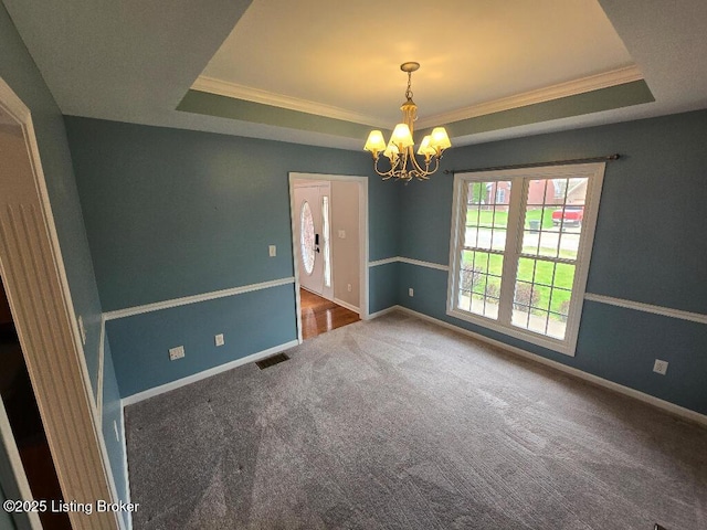 carpeted spare room with a raised ceiling, visible vents, and baseboards