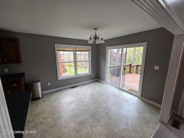 unfurnished dining area featuring a notable chandelier, visible vents, and baseboards