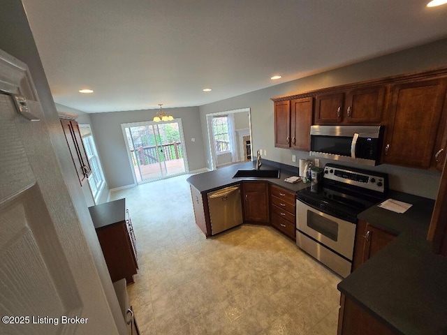 kitchen featuring light floors, appliances with stainless steel finishes, dark countertops, and a sink