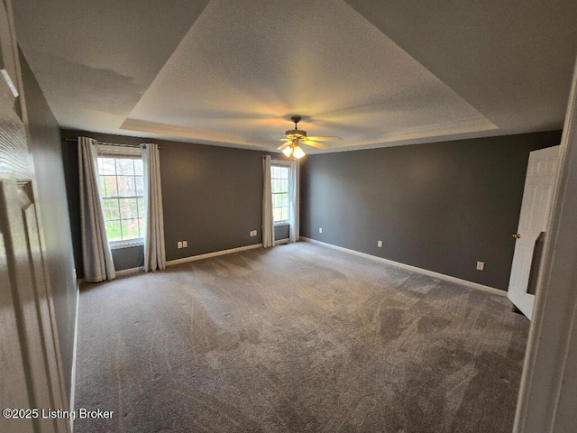 empty room featuring carpet floors, baseboards, a tray ceiling, and a textured ceiling