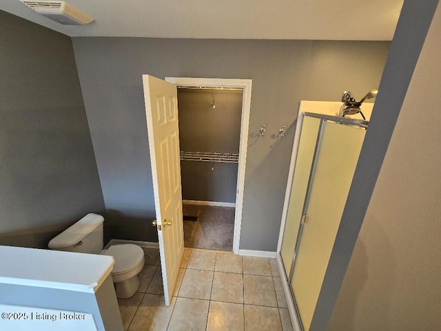 bathroom with tile patterned flooring, toilet, visible vents, baseboards, and a shower stall