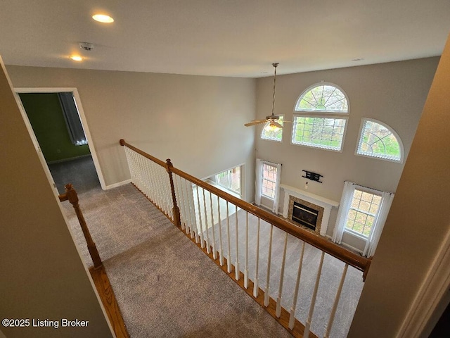 stairs featuring carpet floors, recessed lighting, a tiled fireplace, ceiling fan, and baseboards