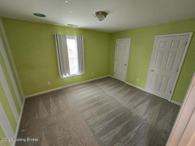 unfurnished bedroom with carpet floors, visible vents, and baseboards