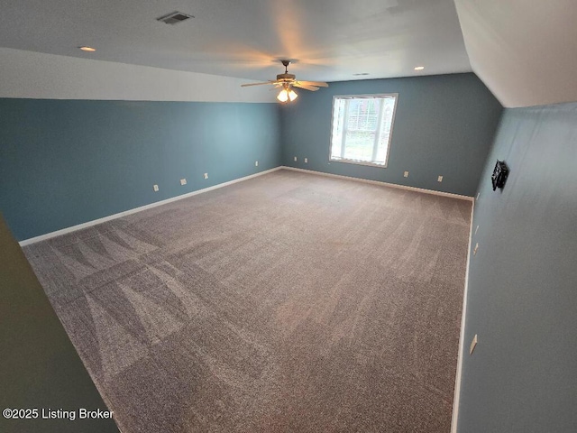 interior space featuring carpet floors, a ceiling fan, visible vents, vaulted ceiling, and baseboards