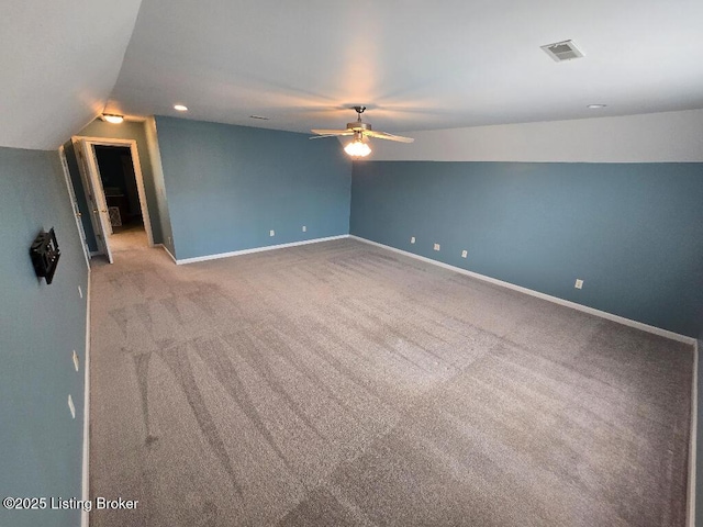 carpeted spare room with a ceiling fan, lofted ceiling, visible vents, and baseboards