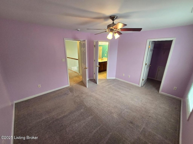 unfurnished bedroom with baseboards, connected bathroom, ceiling fan, a spacious closet, and carpet flooring