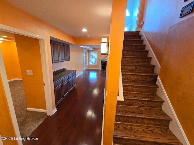 stairway featuring recessed lighting, a tile fireplace, baseboards, and wood finished floors