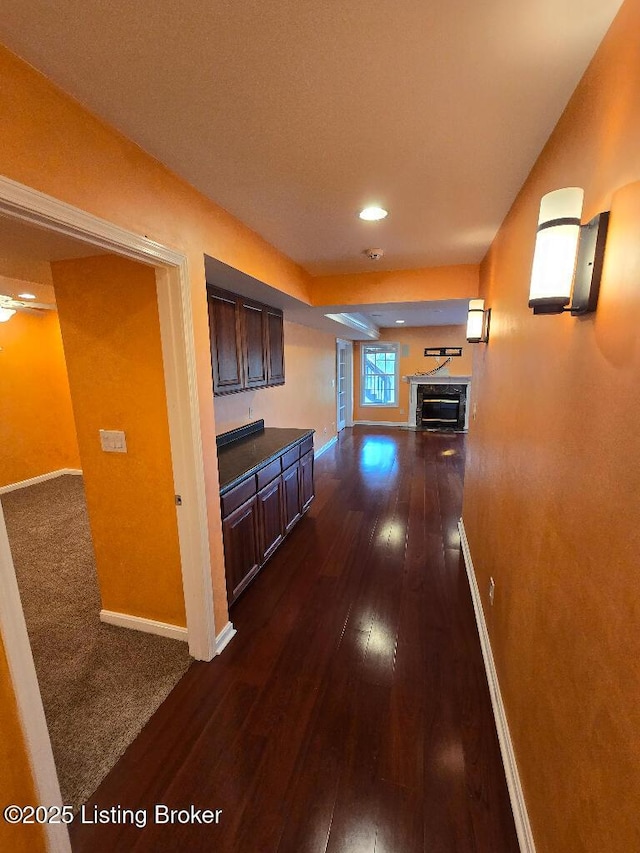 hall featuring dark wood-style flooring and baseboards