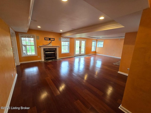 unfurnished living room featuring french doors, a healthy amount of sunlight, baseboards, and wood finished floors