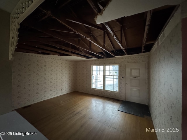 unfurnished room with wallpapered walls and wood finished floors