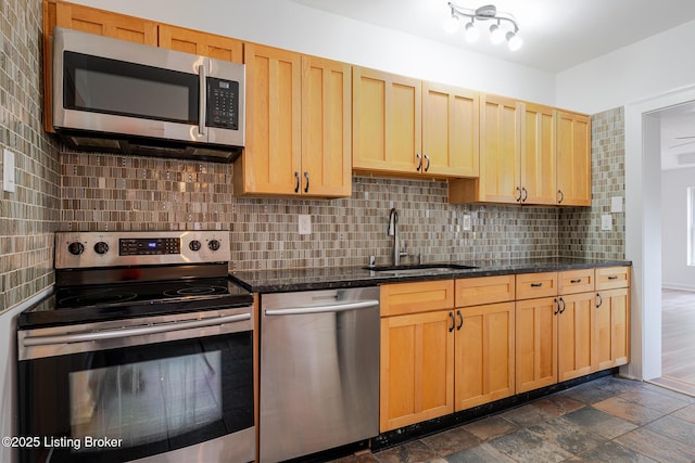 kitchen featuring appliances with stainless steel finishes, light brown cabinets, a sink, and decorative backsplash