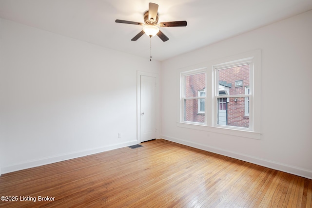 spare room with visible vents, ceiling fan, light wood-style flooring, and baseboards