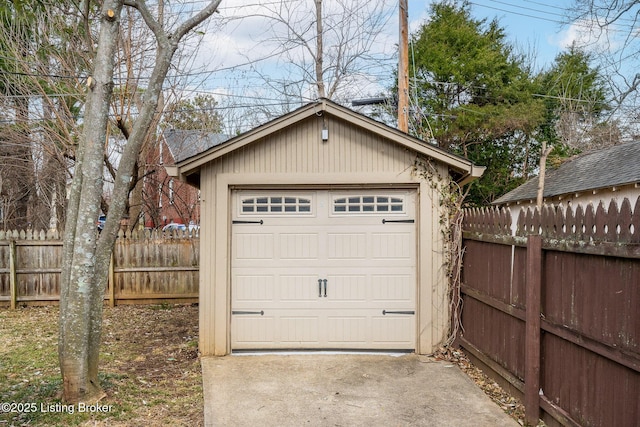 detached garage featuring driveway and fence