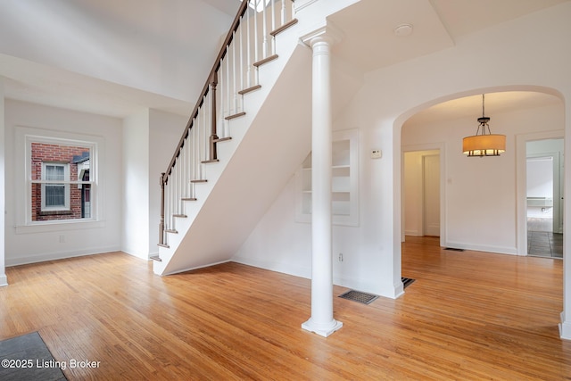 interior space with light wood-style flooring, stairs, visible vents, and baseboards