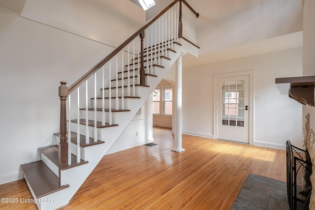 stairs with arched walkways, a high ceiling, wood finished floors, visible vents, and baseboards