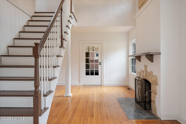 entryway with a fireplace with flush hearth, a high ceiling, wood finished floors, and baseboards