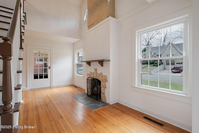 unfurnished living room featuring a wealth of natural light, light wood finished floors, stairs, and visible vents