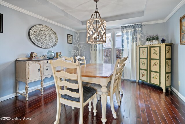 dining area with a tray ceiling, crown molding, baseboards, and wood finished floors