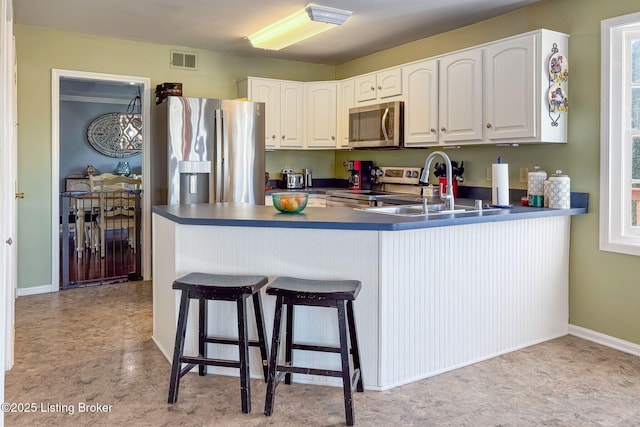 kitchen featuring stainless steel appliances, a peninsula, a sink, visible vents, and white cabinetry