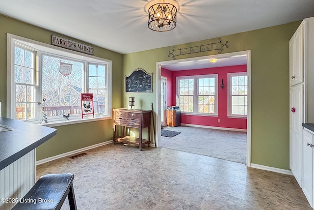 interior space with a chandelier, visible vents, and baseboards