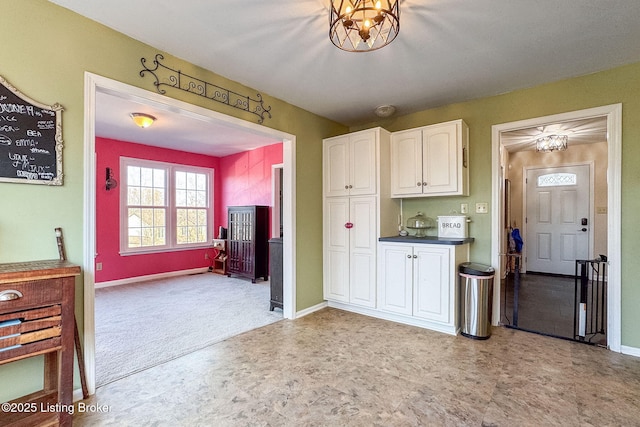 kitchen with an inviting chandelier, dark countertops, white cabinetry, and baseboards