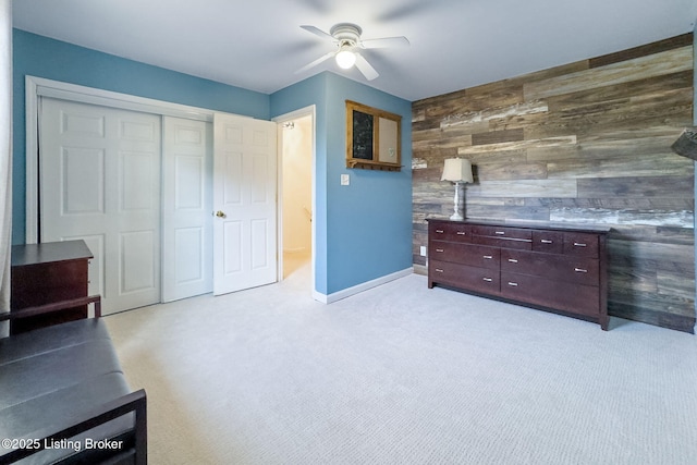 interior space with wooden walls, baseboards, an accent wall, carpet flooring, and a closet