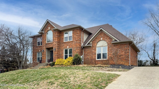 traditional home featuring a shingled roof, brick siding, and a front lawn