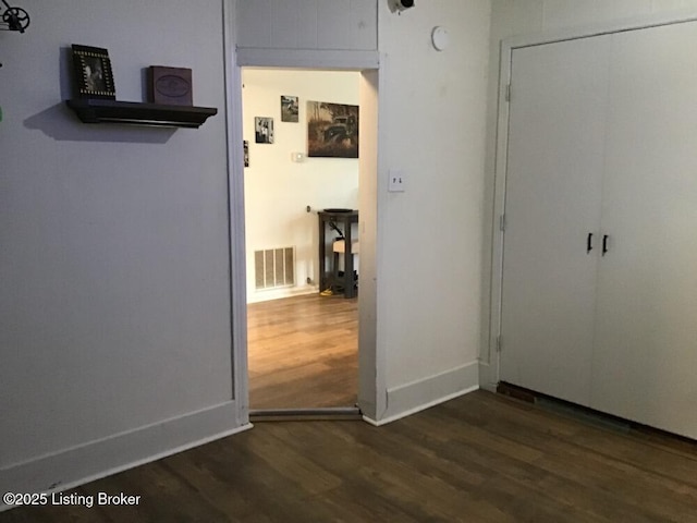 unfurnished bedroom featuring a closet, dark wood finished floors, visible vents, and baseboards