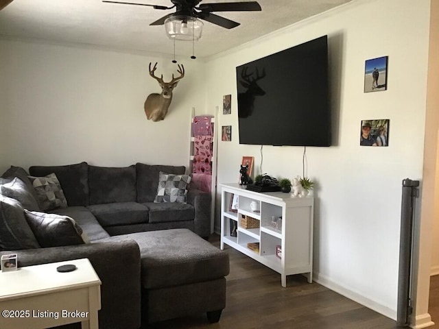 living area featuring dark wood-style floors, ornamental molding, and a ceiling fan