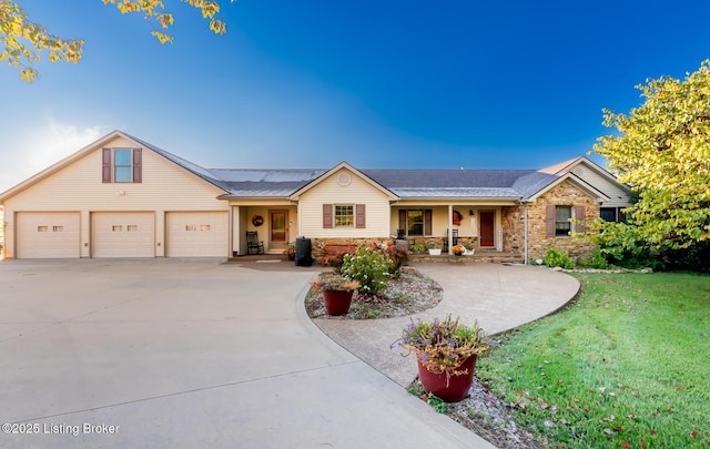 single story home with covered porch, a garage, stone siding, driveway, and a front lawn