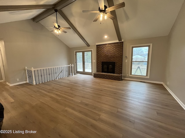 unfurnished living room featuring a fireplace, plenty of natural light, wood finished floors, and beam ceiling