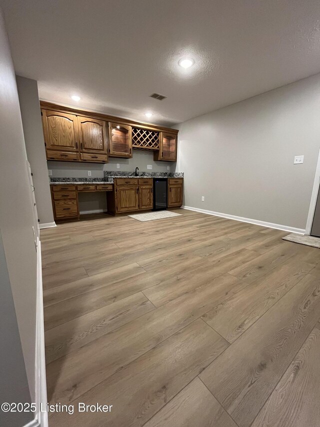 bar featuring a sink, visible vents, baseboards, light wood-type flooring, and indoor wet bar