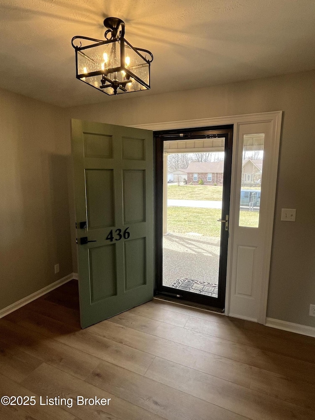 entrance foyer with baseboards, light wood-style flooring, and a notable chandelier