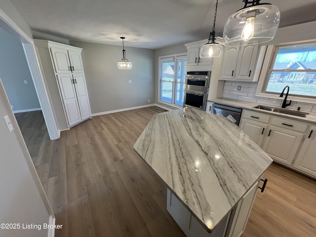 kitchen featuring dishwasher, double oven, a sink, and white cabinetry